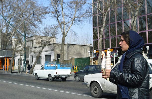 یک دختر ایرانی بستنی در دست از خیابانی در تهران عبور می کند سوم اسفند ۱۳۸۲